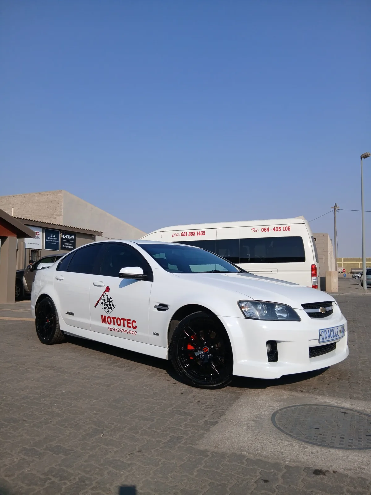 The owner's personal white Chevrolet sedan in Mototec branding, parked outside the workshop