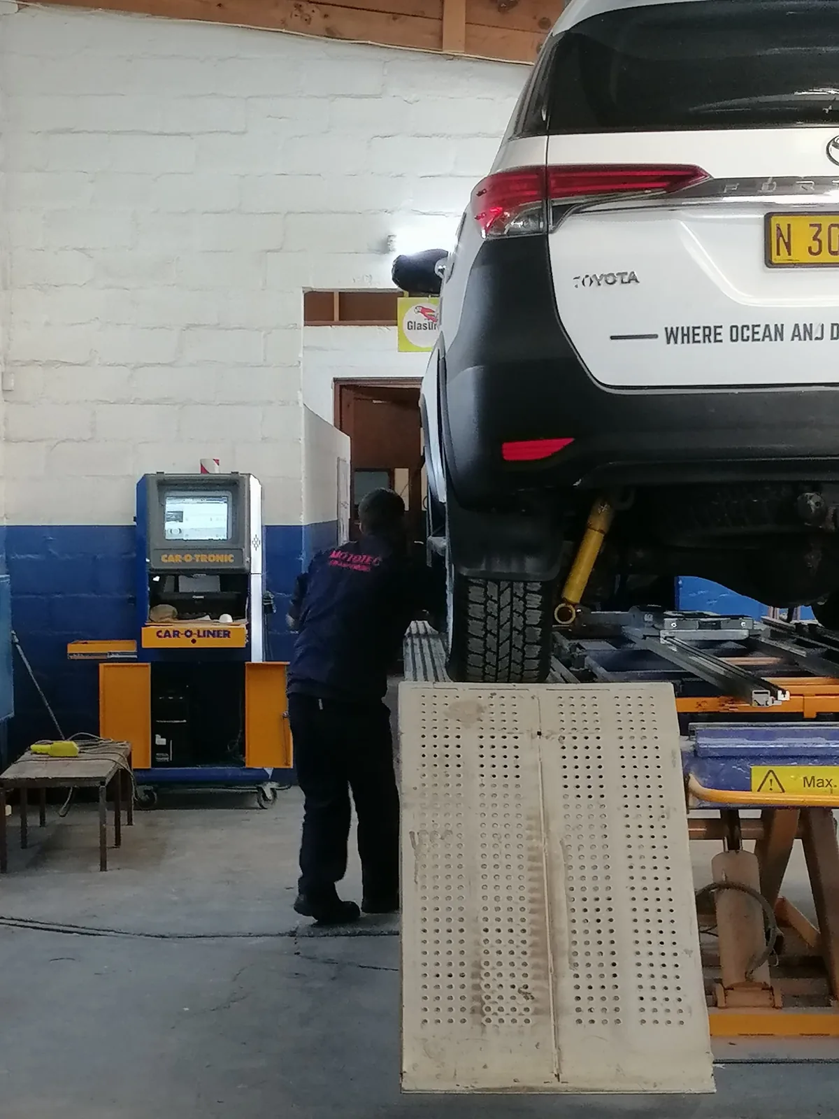 Technician working on an SUV raised on the measuring bench
