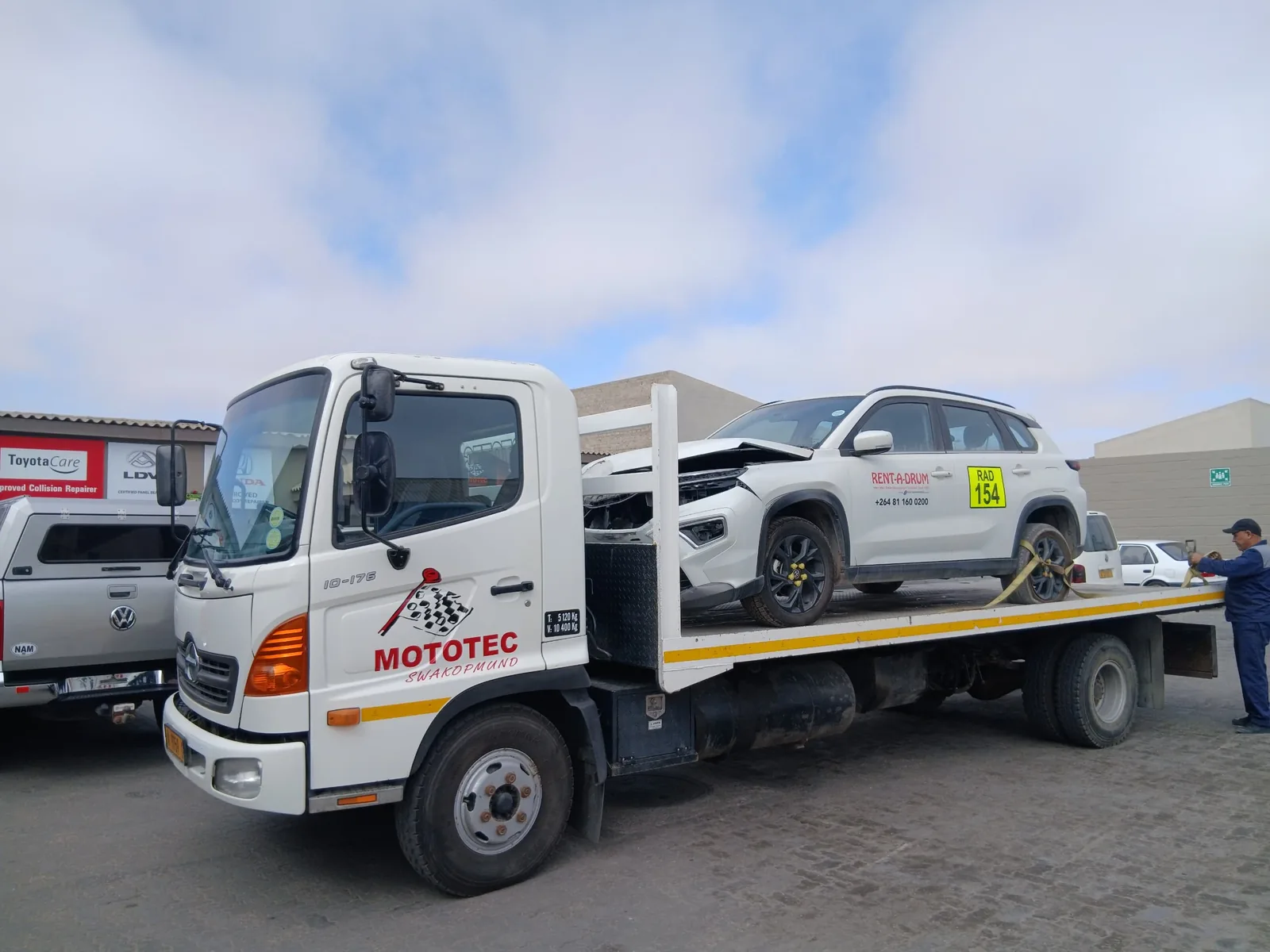Mototec recovery truck carrying a damaged white SUV into the yard