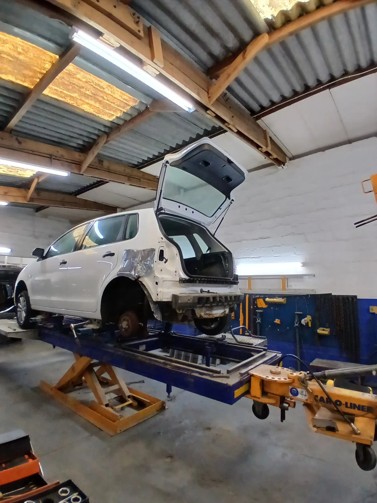 White hatchback mounted on the straightening bench for structural repair
